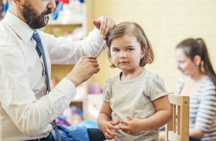 Young father getting his little daughter ready in a morning