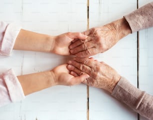 Unrecognizable grandmother and her granddaughter holding hands.