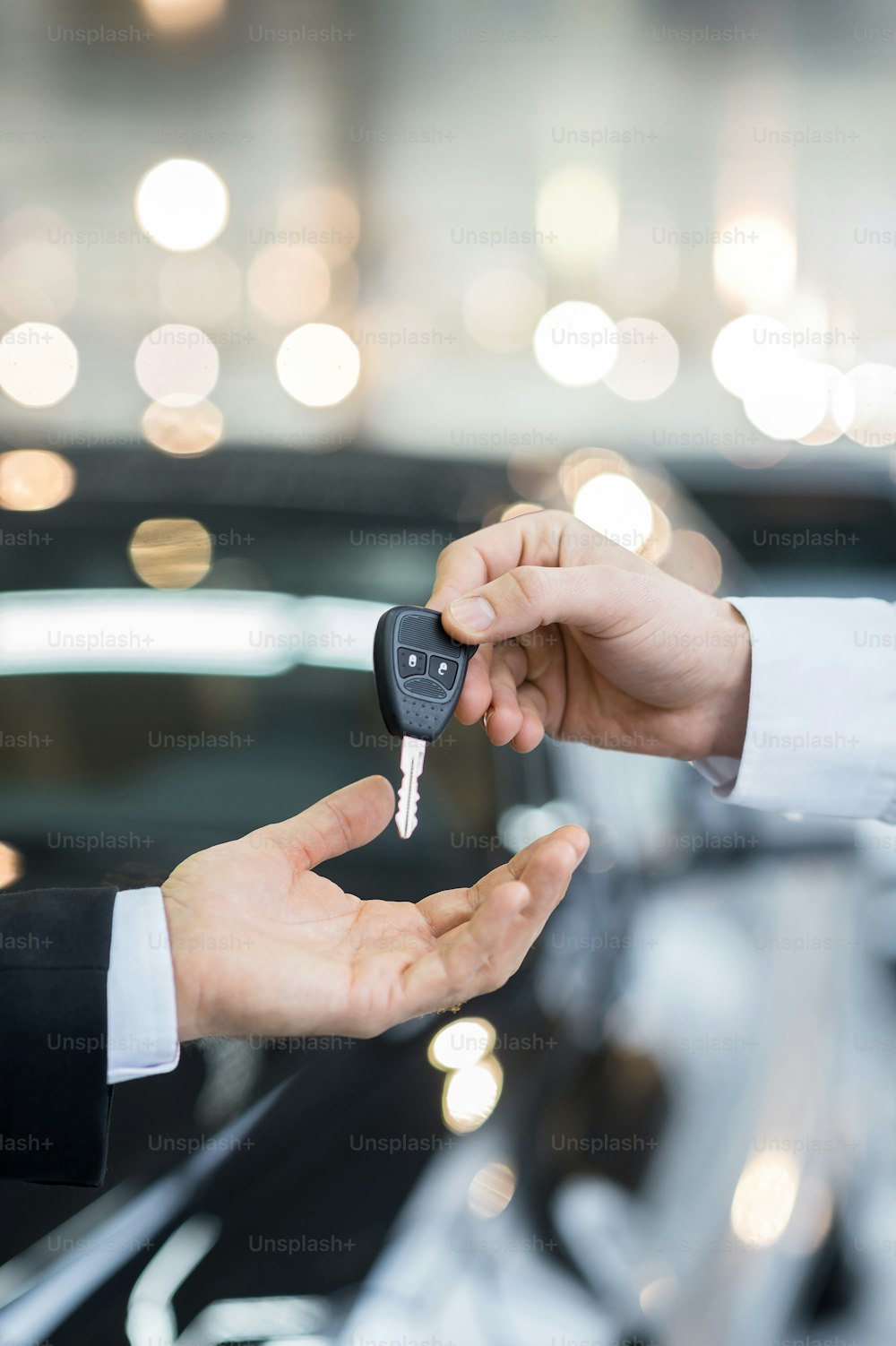 Close up of man giving key to the car owner while standing in front of a car