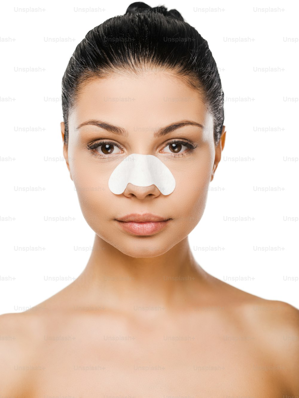 Beautiful young woman with clear-up patches on her nose looking at camera while standing against white background