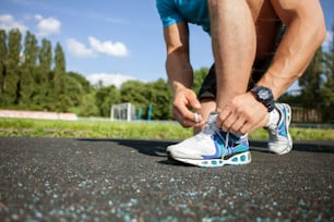 Close up of legs of sportsman tying the laces in stadium. There is copy space in left side