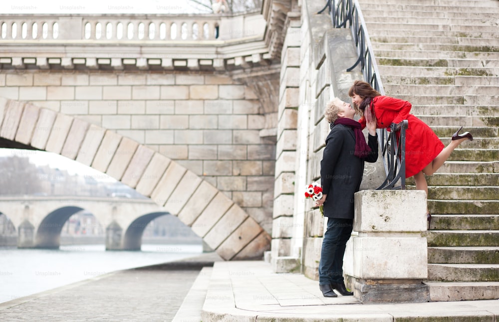 Beautiful romantic couple kissing on a Parisian embankment at spring or winter