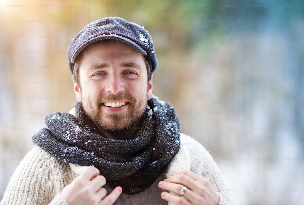 冬の自然の中でウールのセーターを着たハンサムな若い男