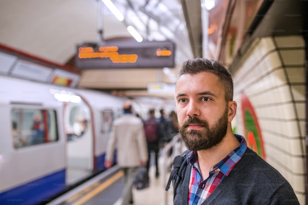 Close up of young hipster man standing at the underground platform waiting