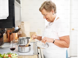 abuela cocinando en la cocina con cuchara de madera.