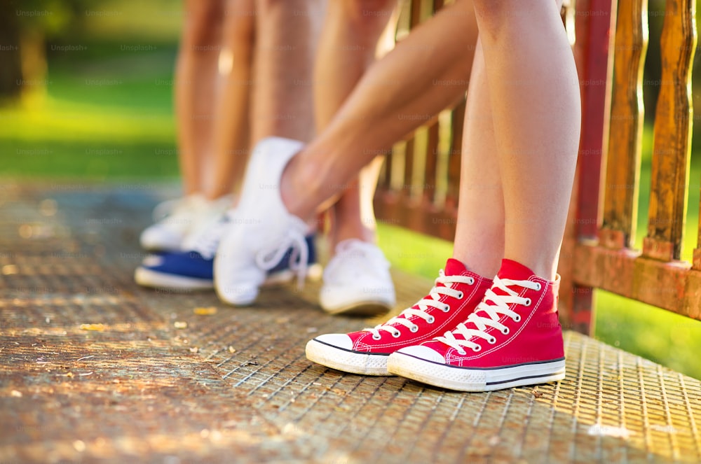 Gambe e scarpe da ginnastica di ragazzi e ragazze adolescenti in piedi sul marciapiede