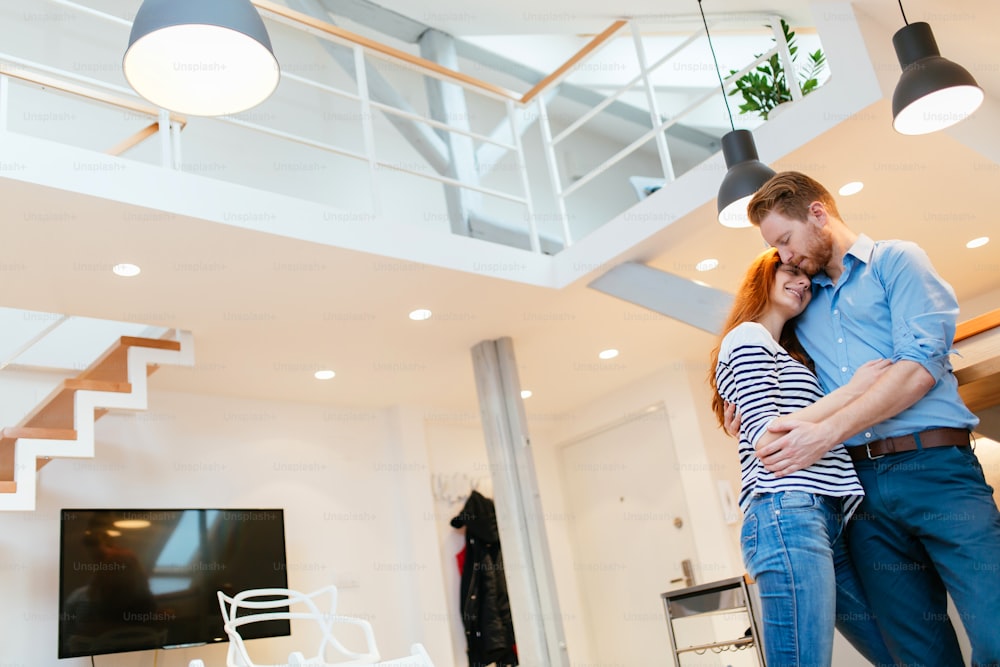 Couple enjoying their new luxurious home and hugging in living room