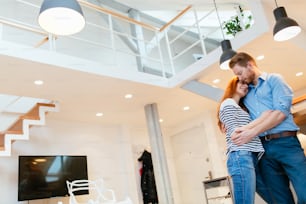 Paar genießt sein neues luxuriöses Zuhause und umarmt sich im Wohnzimmer