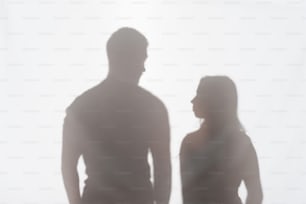 Silhouette von Mann und Frau, die auf weißem Hintergrund stehen und sich gegenseitig ansehen