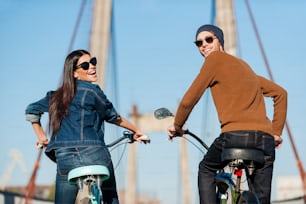 自転車に乗り、笑顔で肩越しに見ている美しい若いカップルの後ろ姿
