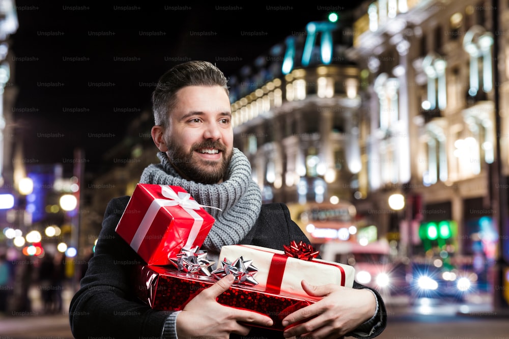 Jeune bel homme avec des cadeaux de Noël dans la ville