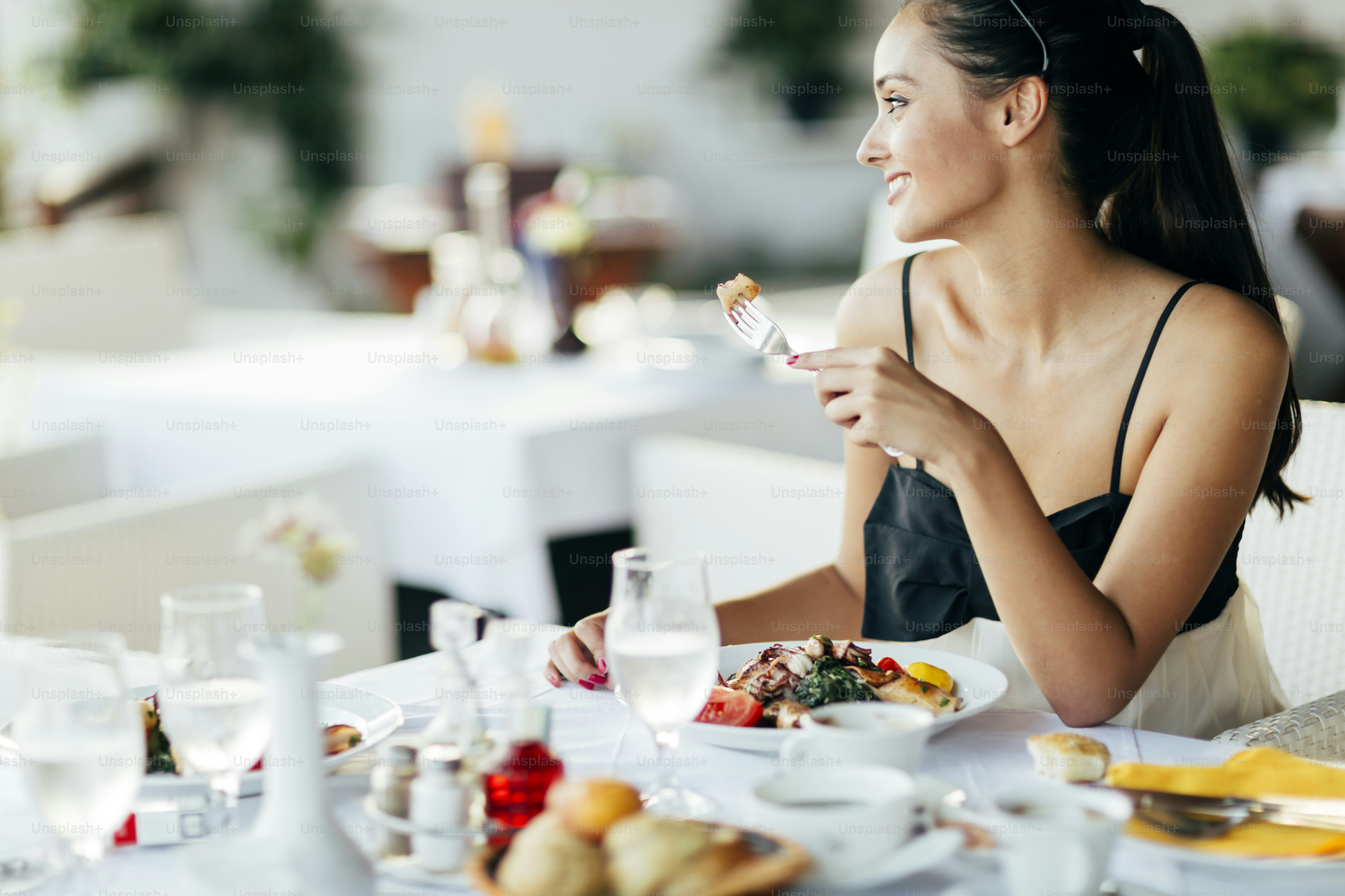 Mujer hermosa comiendo comida en el restaurante durante la puesta del sol