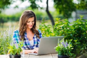 Beautiful gardener with notebook sitting at the table, managing supplies, green sunny nature