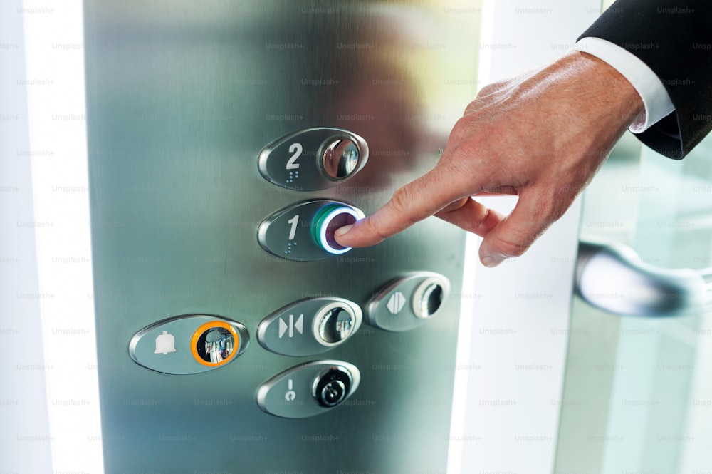 Gros plan d’un bouton de poussée de la main masculine de l’ascenseur