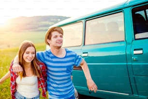 Young teenage couple in love, boy and girl, boyfriend and girlfriend, running outside in green nature, old green campervan