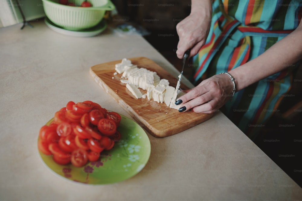 Donna che taglia il formaggio su una tavola di legno