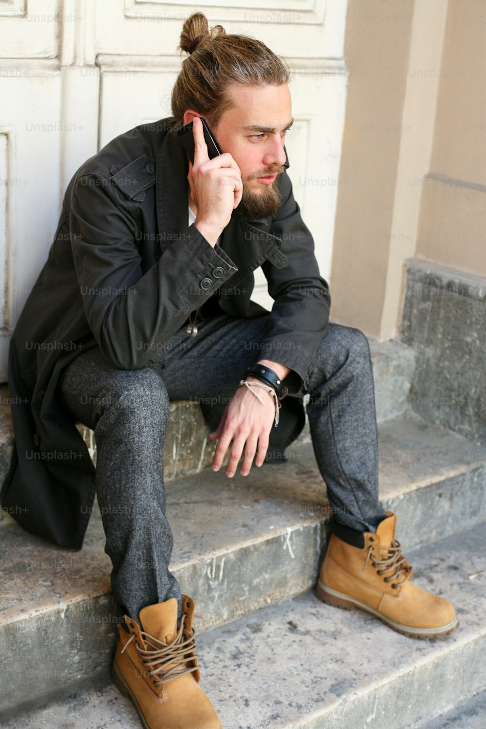 Young man sitting on stairs and talking on smart phone outdoor.  View from above.