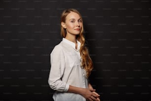 Portrait de fille attrayante dans une chemise blanche sur fond noir