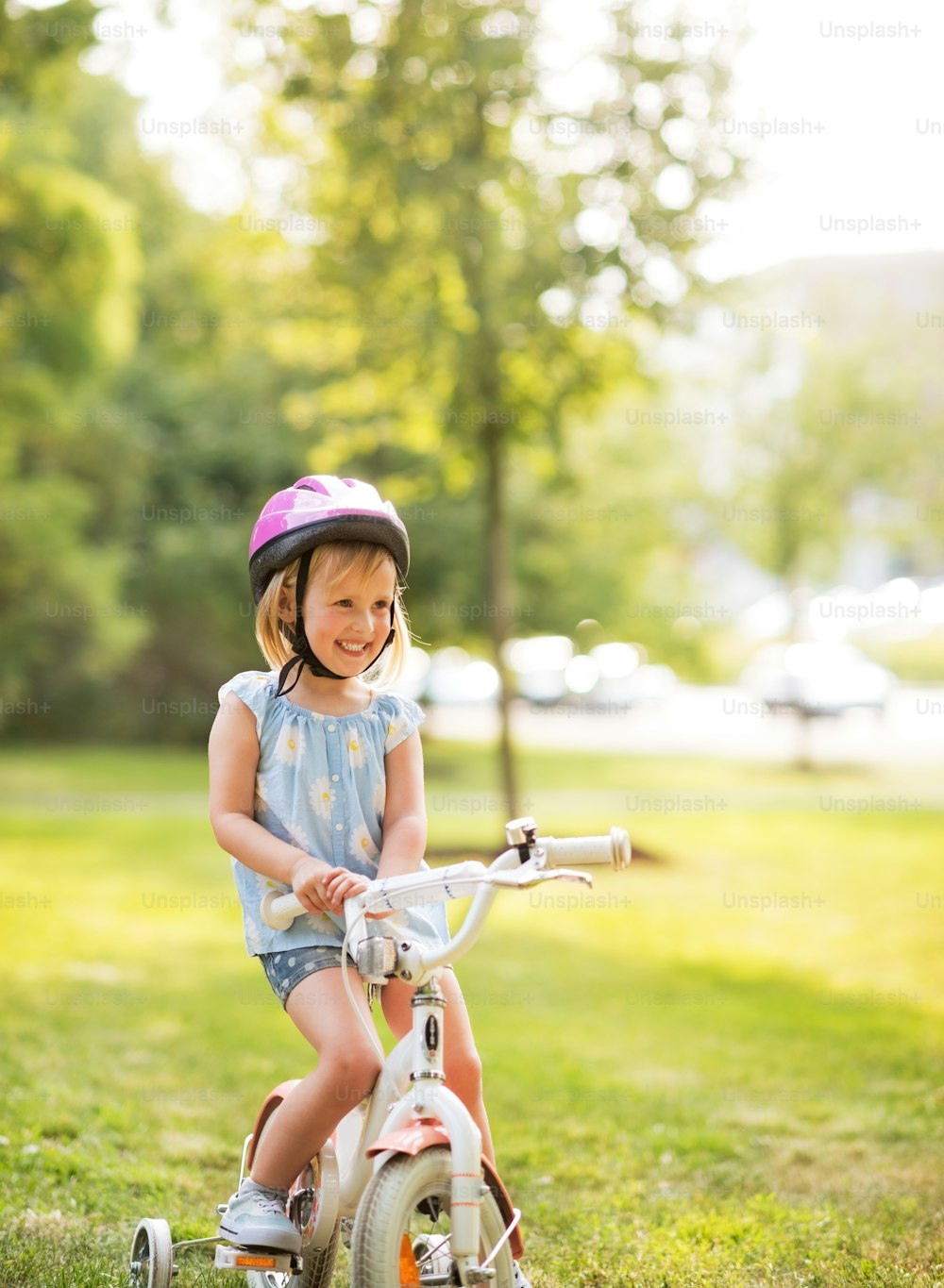 Portrait of smiling baby girl with bicycle in park