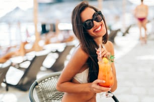 Beautiful woman drinking cocktail in summer and laughing
