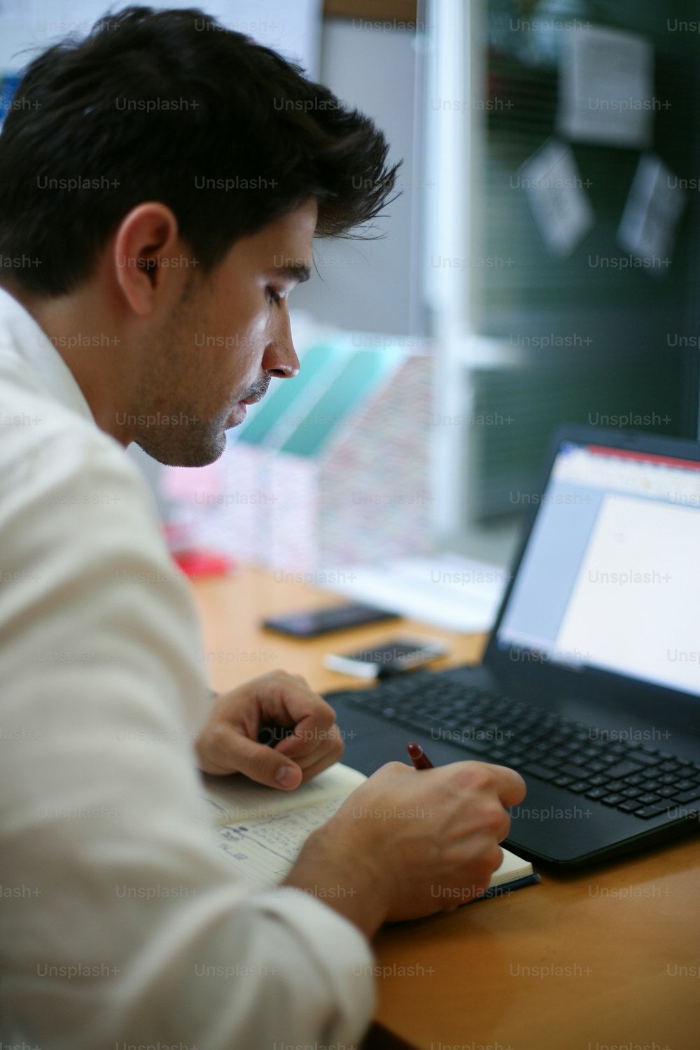 Jeune designer travaillant sur un ordinateur portable dans son bureau. Vue d’en haut.