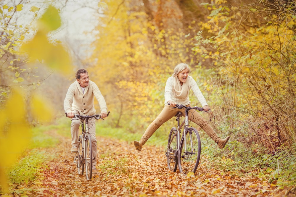 Active seniors riding bike in autumn nature. They having fun outdoor.