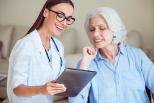 Aiuto per gli anziani. Medico sorridente e allegro con tablet pc computer e donna anziana positiva