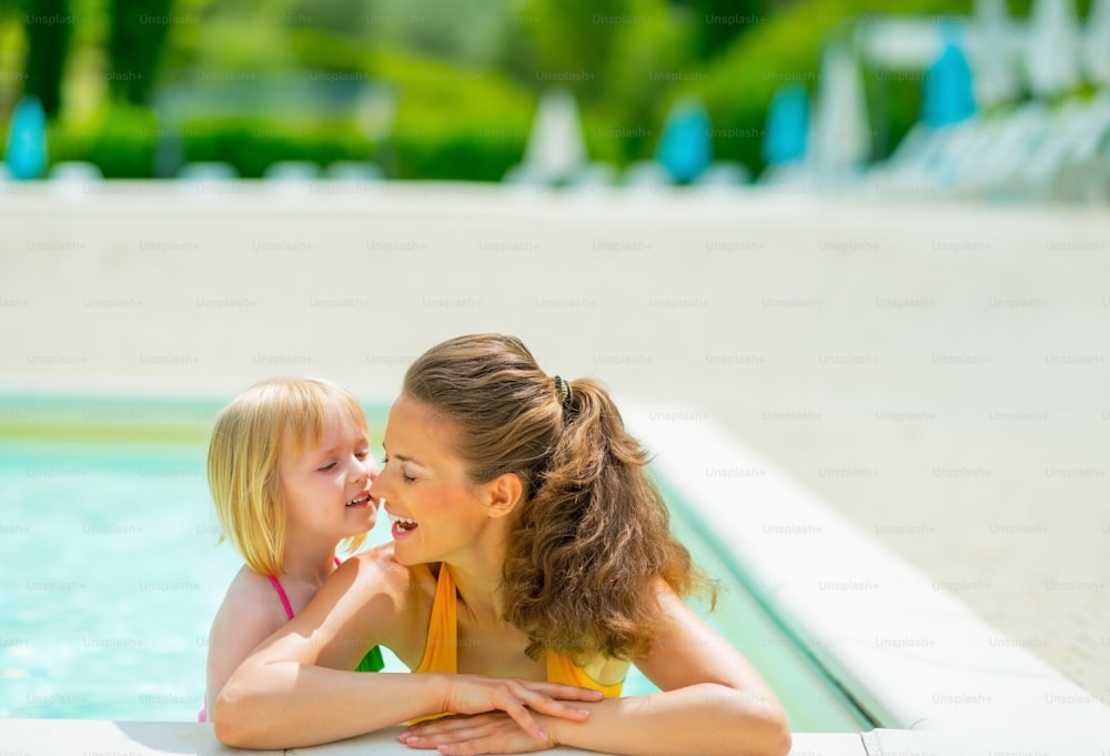 Portrait of happy mother and baby girl in swimming pool