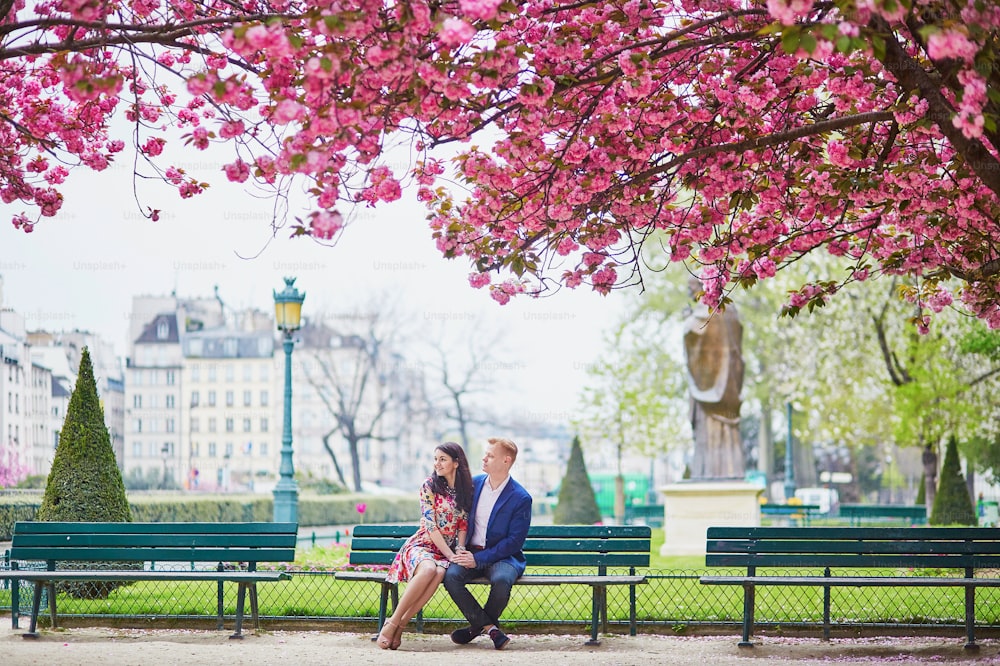 Junges verliebtes Paar mit einem Date unter rosa Kirschblütenbäumen. Touristen, die Paris im Frühling besuchen