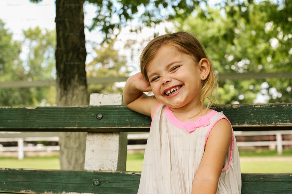 Cheerful little girl sitting in the park and looking at camera. Space for copy.