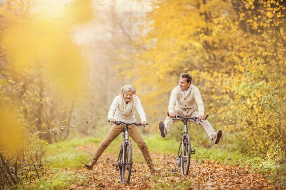 Anziani attivi in bicicletta nella natura autunnale. Si divertono all'aperto.