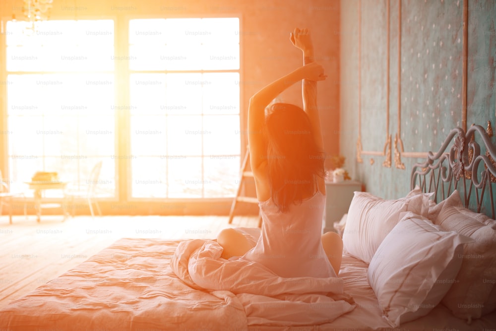 Woman stretching in bed after wake up, back view. Model is posing in lingerie