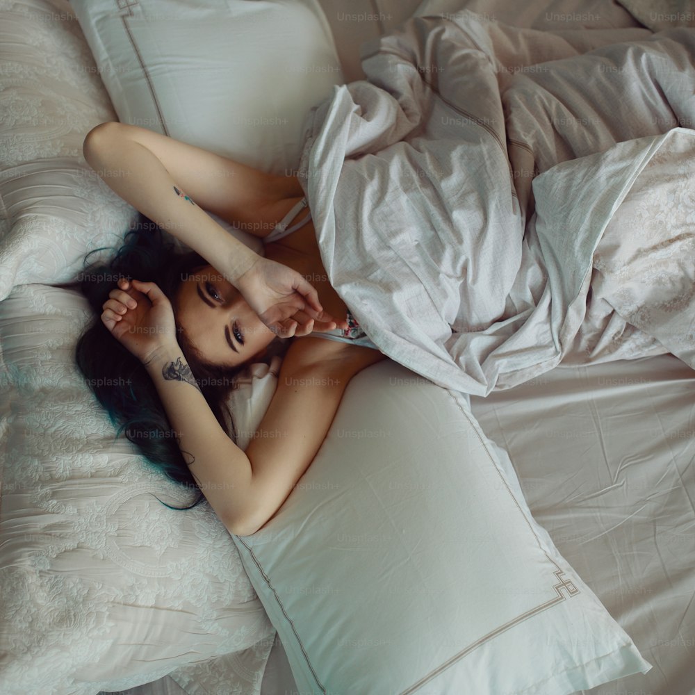 Frau streckt sich nach dem Aufwachen im Bett, Draufsicht