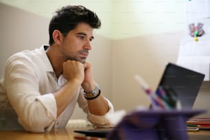 ホームオフィスでノートパソコ��ンで作業する若いビジネスマン。セピア色。