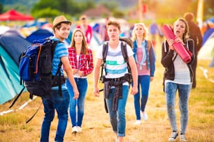 Group of beautiful teenagers with backpacks arriving at summer music festival