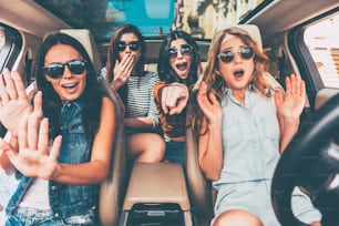 Cuatro mujeres jóvenes gesticulando y luciendo aterrorizadas mientras están sentadas juntas en el auto