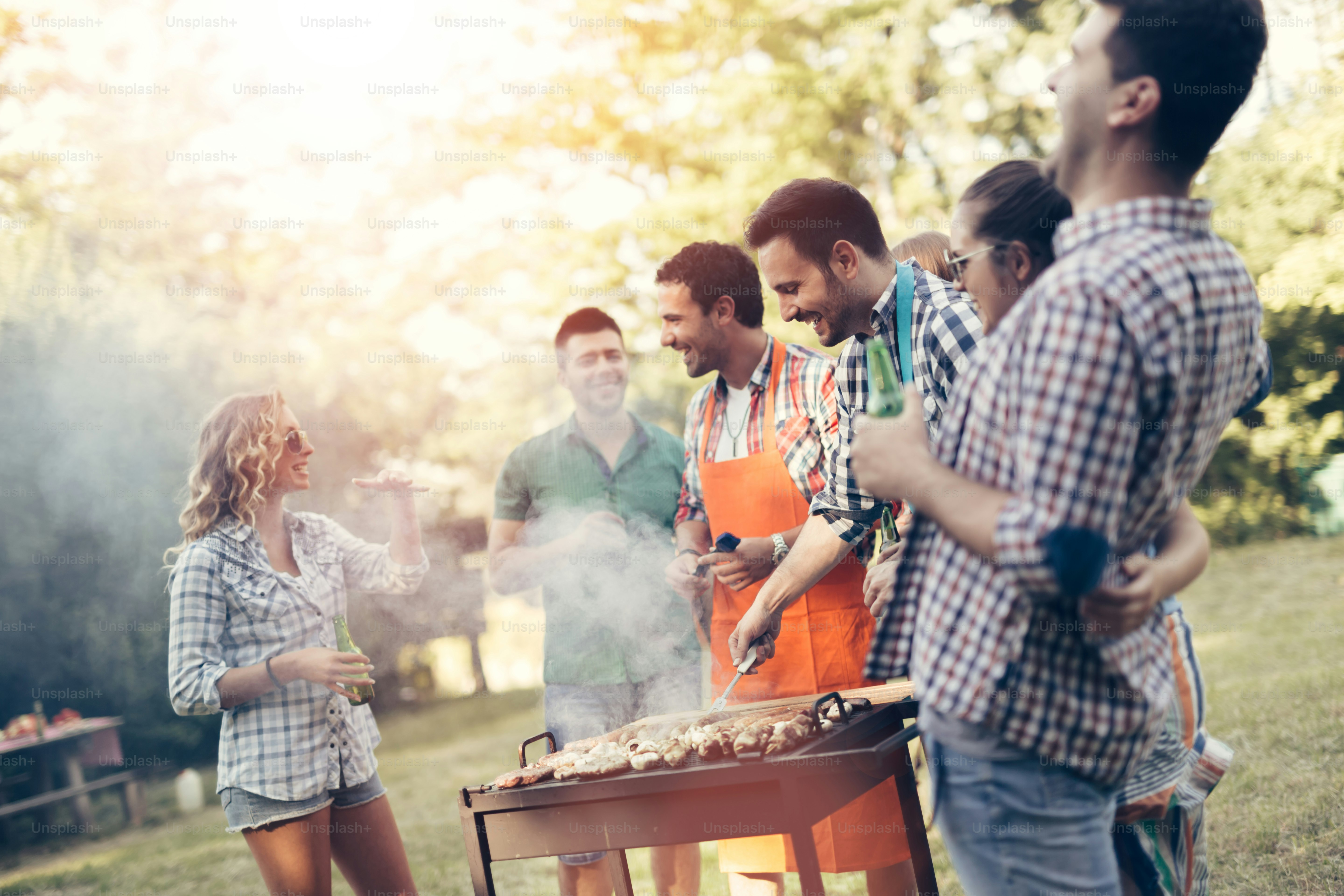 Des amis qui font un barbecue dans la nature tout en s’amusant