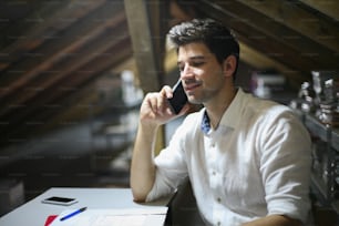 Young architect using phone at his workplace.