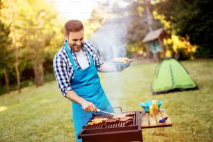 Handsome man preparing barbecue for friends