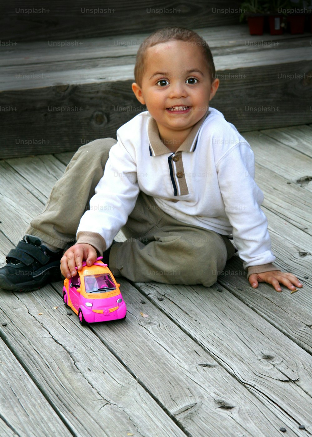 a young boy sitting on the ground with a toy car