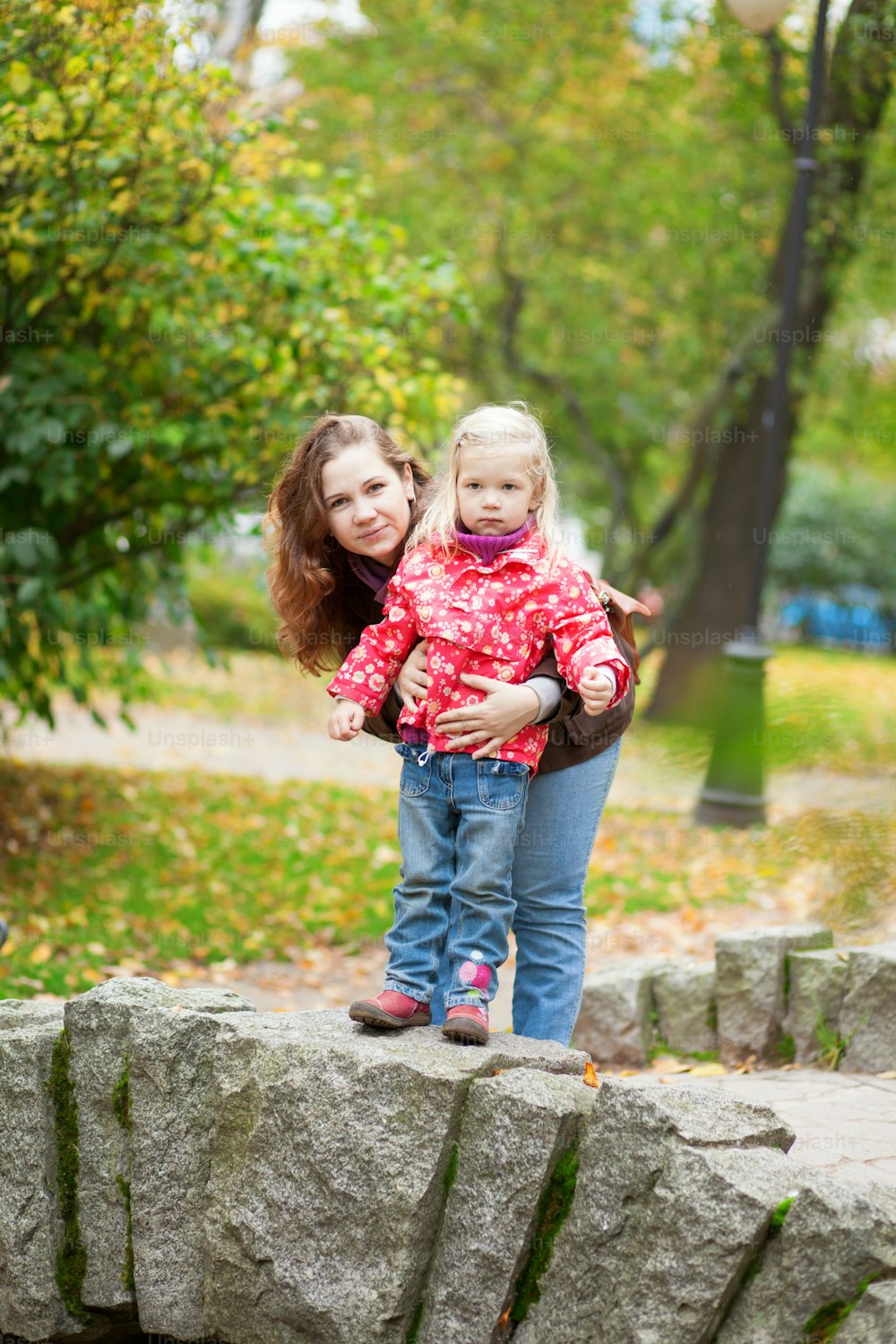 Outdoor portrait of beautiful mother and daughter on a little bridge