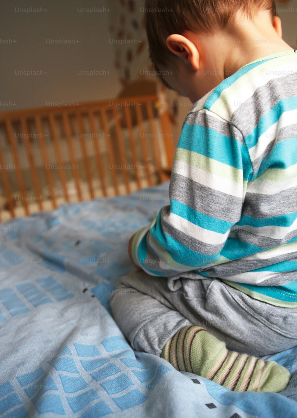 Rear view sad little boy on the bed, natural light