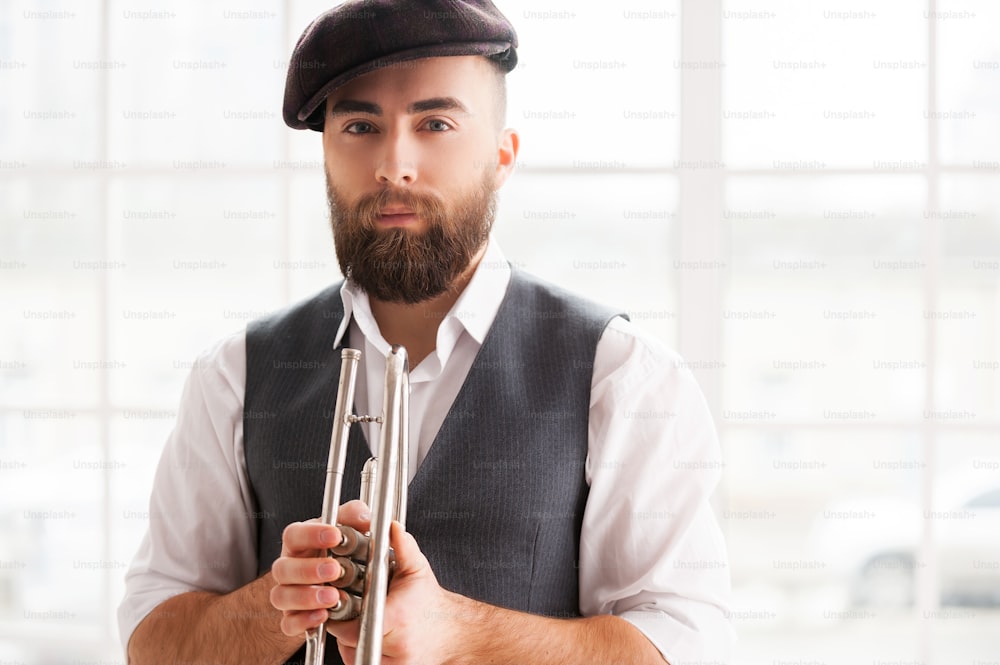 Handsome young bearded men standing with trumpet in his hands
