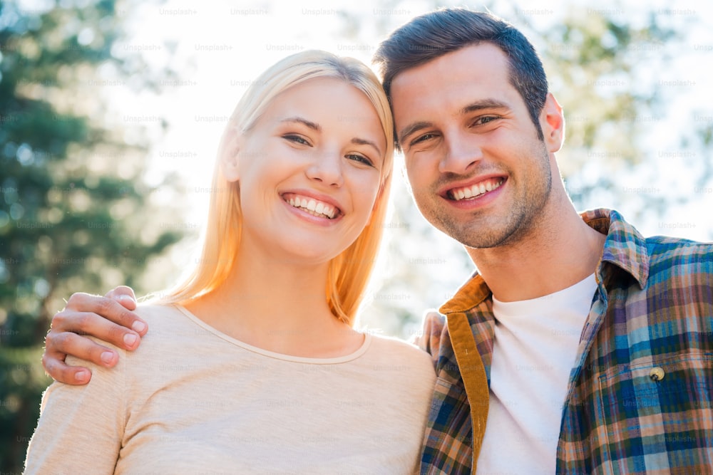 Low angle view of beautiful young couple bonding to each other and smiling while standing outdoors