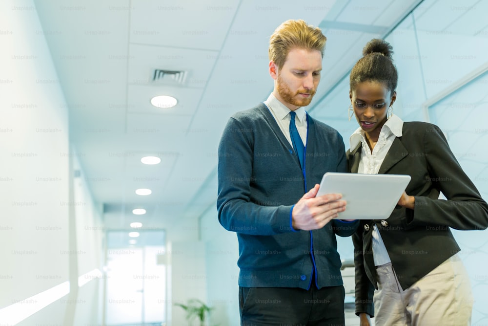 Business partners and colleagues discussing ideas displayed on a tablet on an office corridor