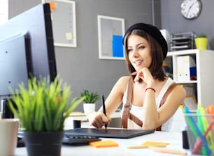 컴퓨터로 작업하는 동안 그래픽 태블릿을 사용하는 젊은 여성 디자이너