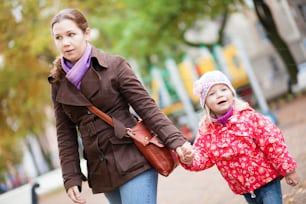 Mother and her adorable daughter walking together hand in hand