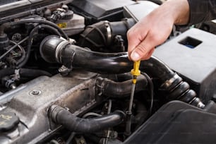 A mechanic checks the oil on a car being repaired