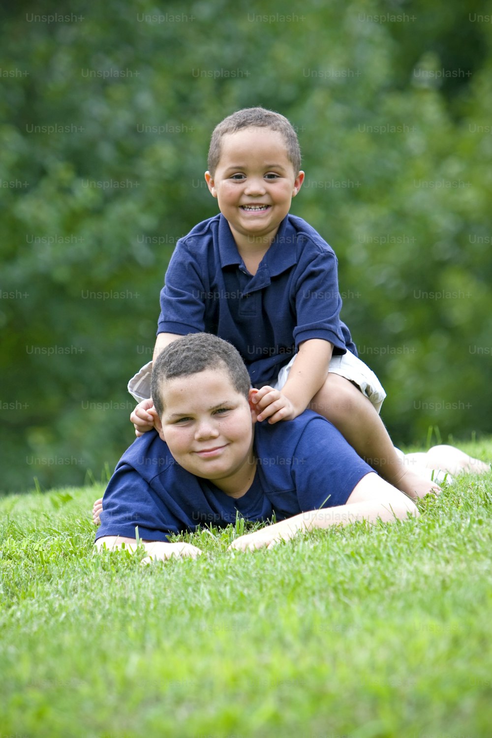 two young boys are sitting on the grass
