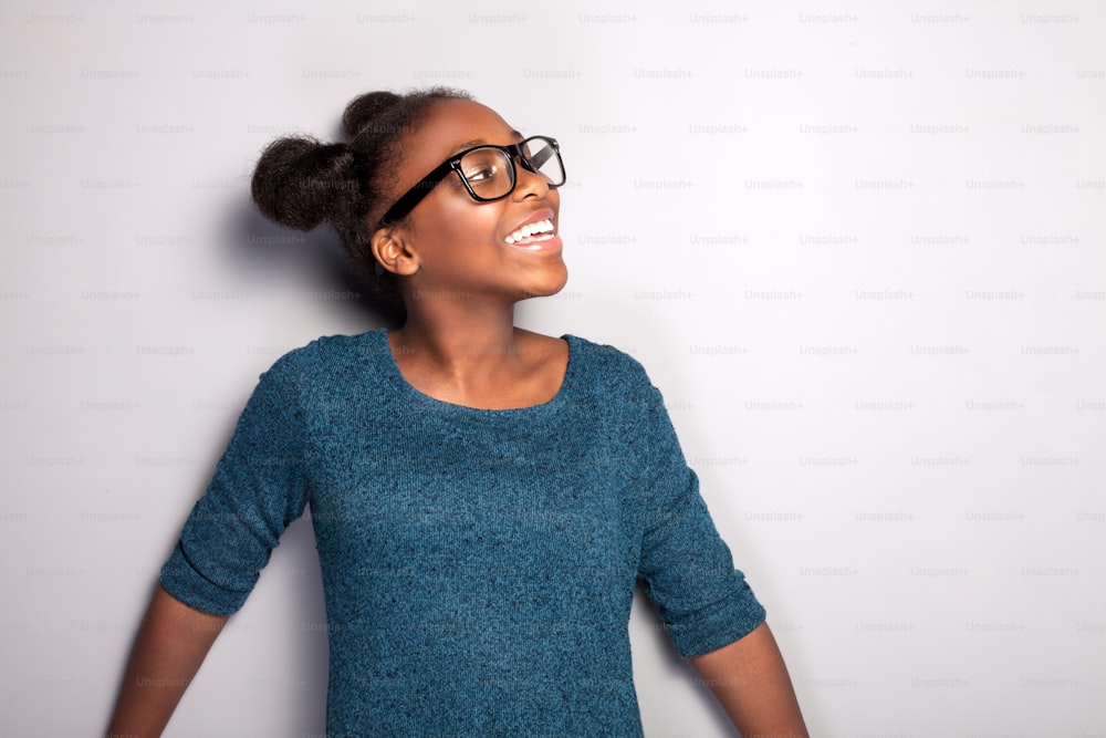 Portrait of happy beautiful african young girl with toothy smile. Teenage girl posing in studio, wearing fashionable eyeglasses.